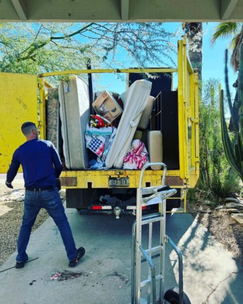 Man unloading junk removal truck filled with mattresses, boxes, and blankets in North Dallas, Texas as part of our junk removal services.